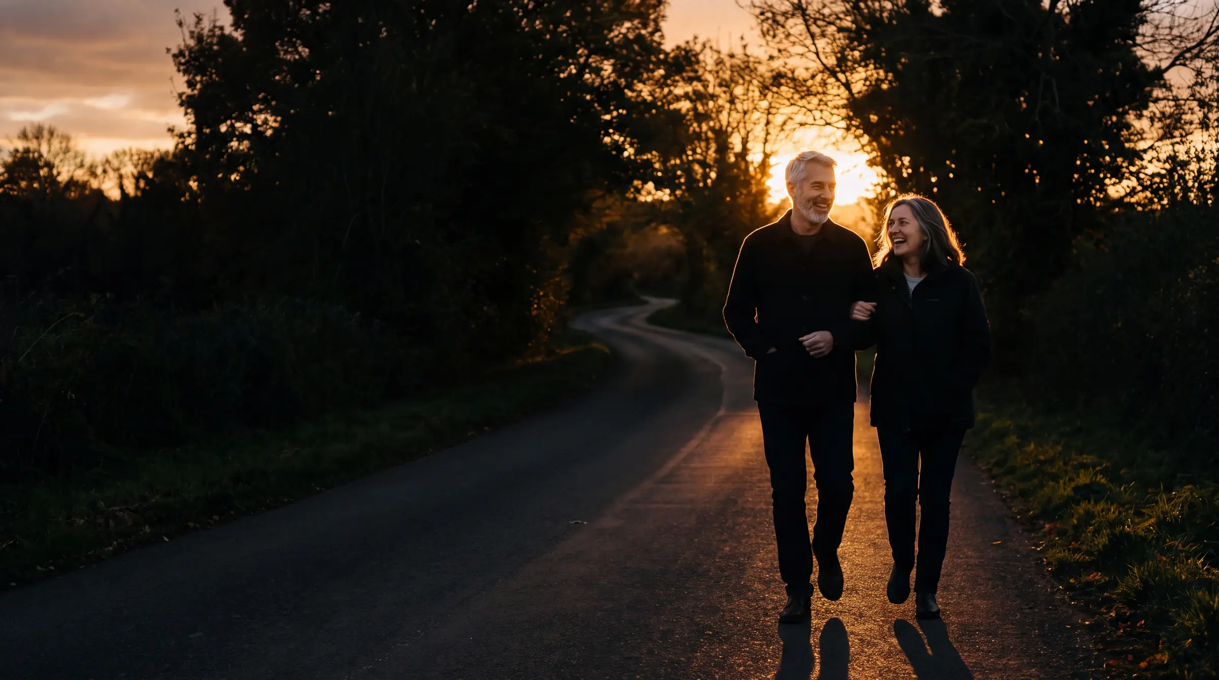 A couple walking together on a wooded path at golden hour